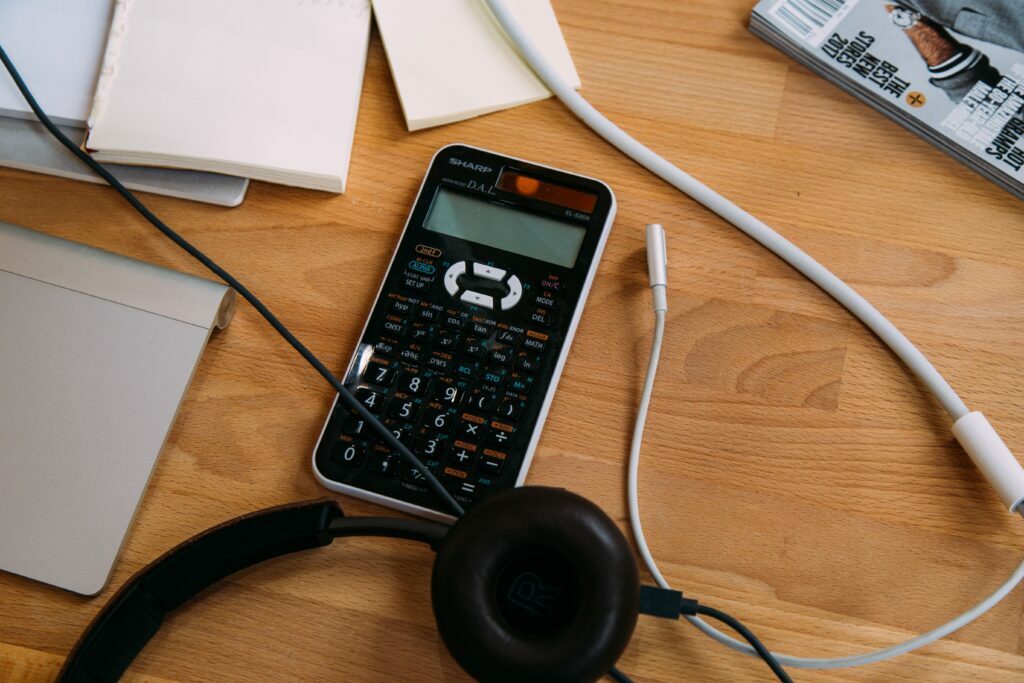 Scientific calculator next to headphones and cables