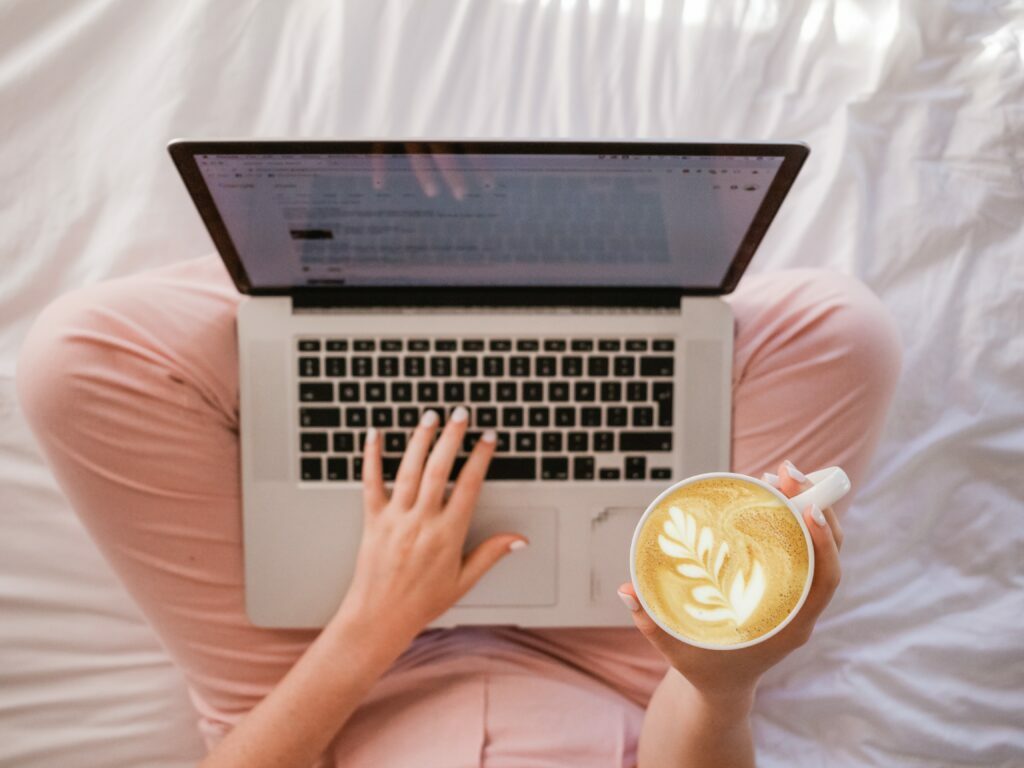 Blogger woman in bed with laptop and coffee